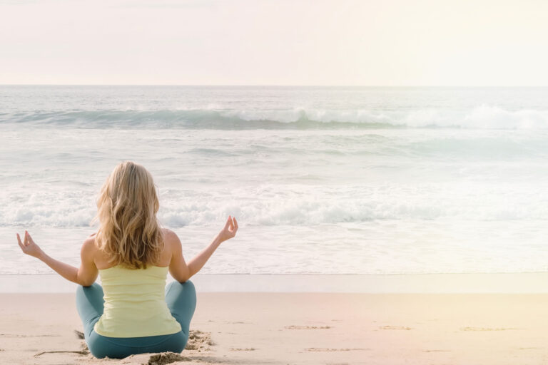 Femme faisant de la méditation et des respirations sur la plage