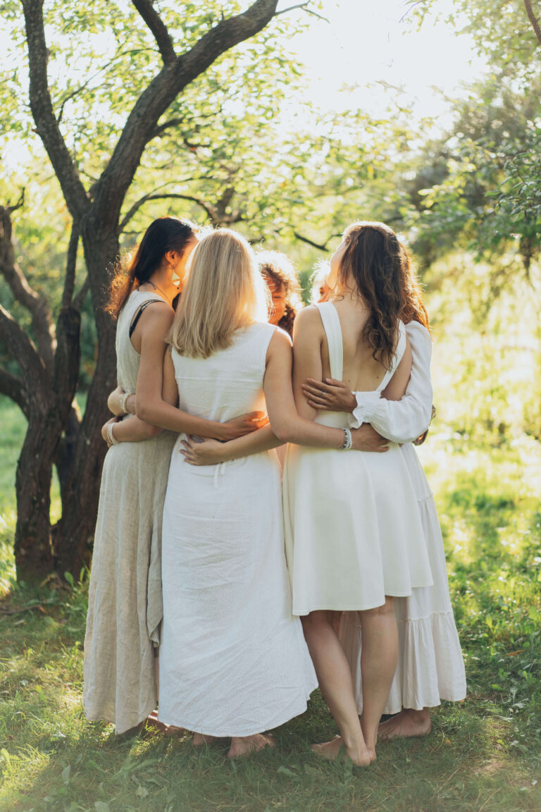 Cercle de femme habillées en robe blanche se prenant dans les bras