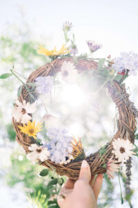 Femme qui tient une couronne de fleur blanche, violette et jaune